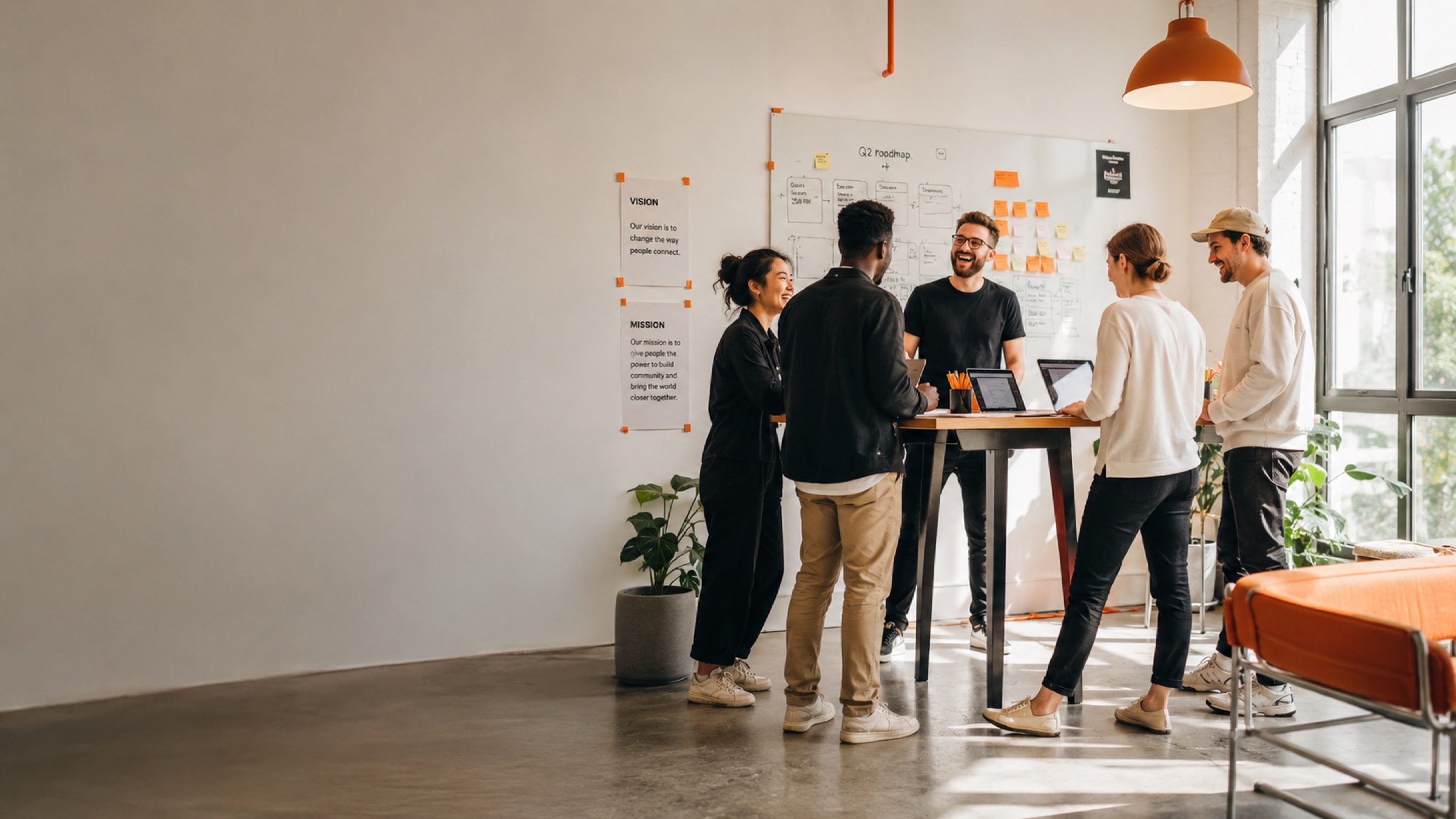 A small product team collaborating at a standing desk with a whiteboard