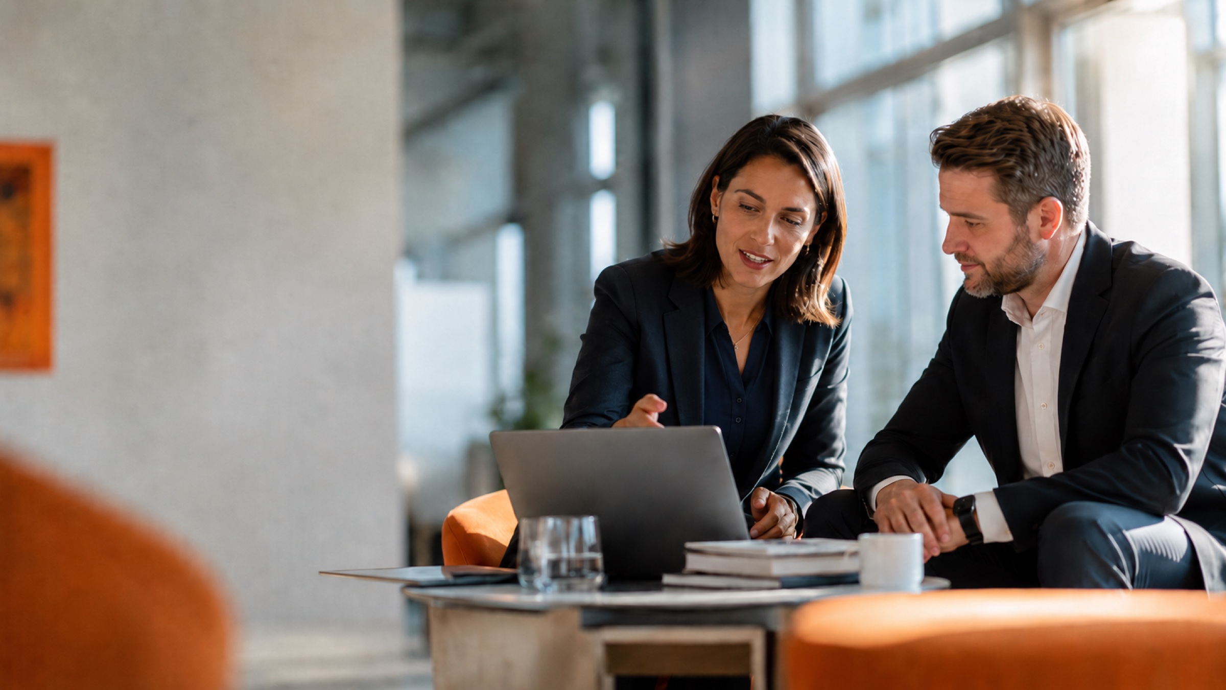 Two business partners collaborating over a laptop in a modern meeting space