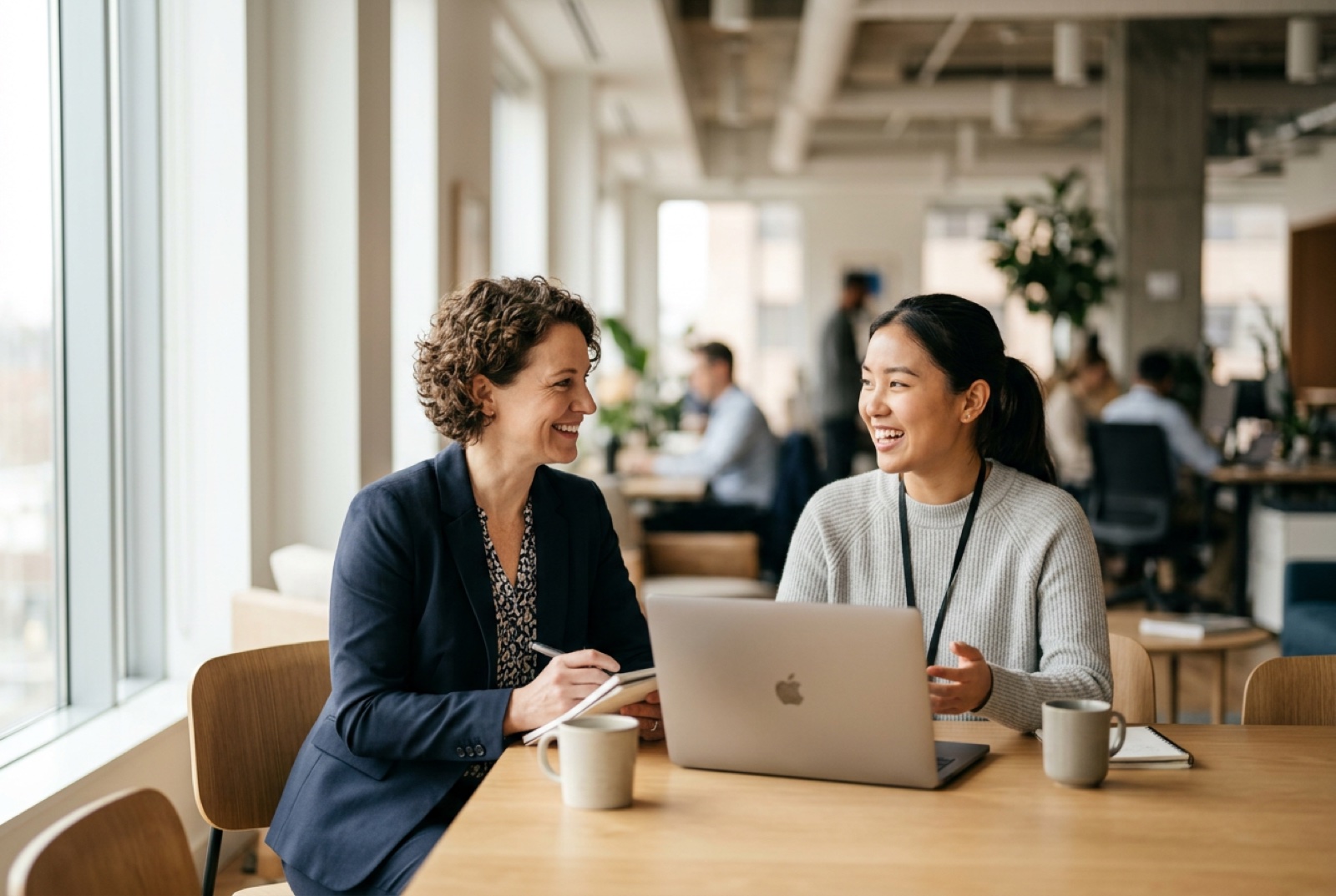 A manager and employee in a positive performance review at a table with a laptop, natural light